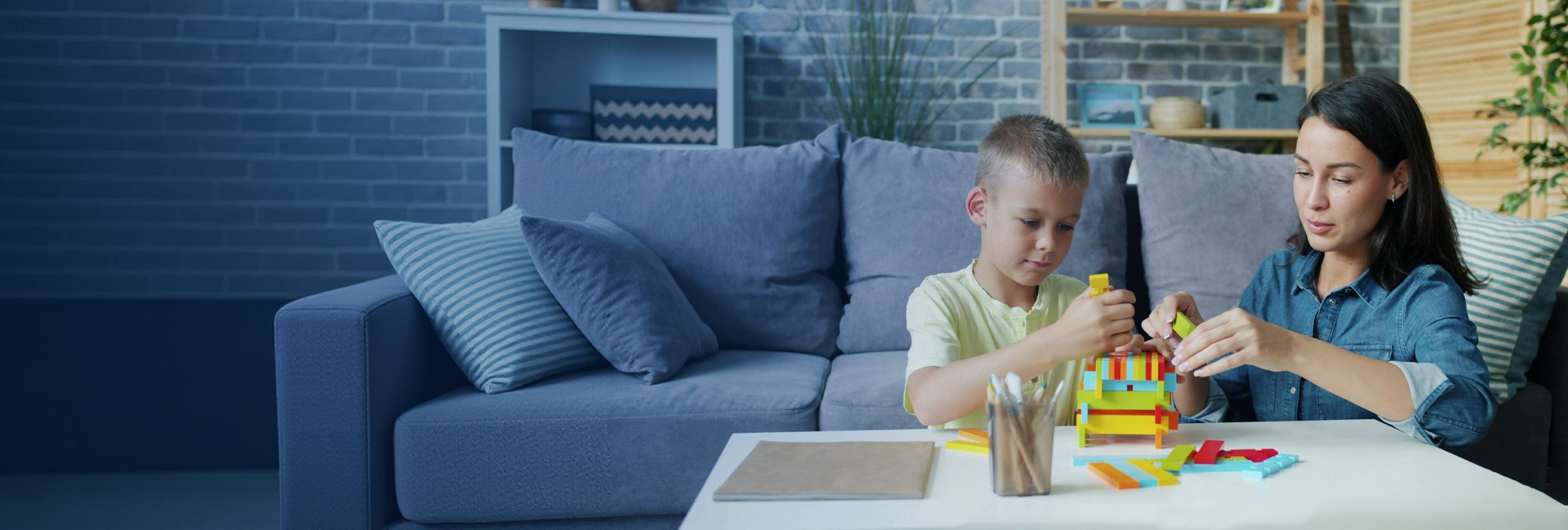 Woman and child playing with building blocks on a table in a living room.